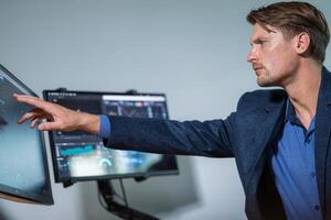 Man analyzing data on touchscreen monitor in modern office environment during work hours photo