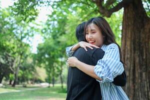 Happy Couple Hugging Outdoors in Park on a Sunny Day, Joyful Hug Between Two People in a Green Park Setting photo