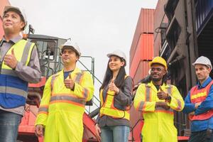 Group of engineer and foreman worker team showing thumbs up in industry containers yard, Success teamwork concepts photo