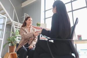 Business handshake. Asian business people making a handshake, Happy business woman manager handshaking greeting client in office photo
