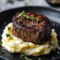 Piece of meat is on top of mashed potatoes and herbs photo