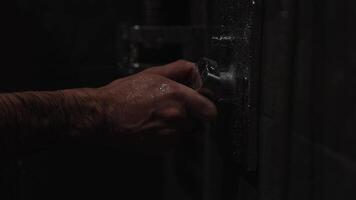 A sleek, dark shower fixture with visible water droplets in a luxurious bathroom setting. Subdued lighting enhances the elegant ambiance. video