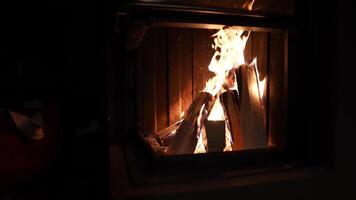 A close up view of burning logs and vibrant flames flickering in a darkened room, highlighting the warmth and comfort of an indoor setting. video