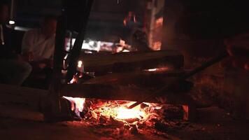 A cozy indoor scene featuring a crackling fireplace with glowing orange and red embers, flickering flames, and rising sparks in a dimly lit setting. video