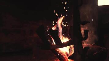 A close up view of burning logs in a fireplace with flickering flames, glowing embers, and gentle smoke rising in a tranquil indoor setting. video