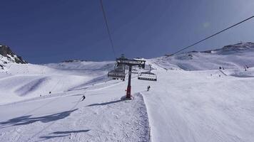 Snow covered slopes in Zermatt, Switzerland, with ski lifts moving and skiers descending. Fencing and markers line the paths in a scenic alpine setting. video
