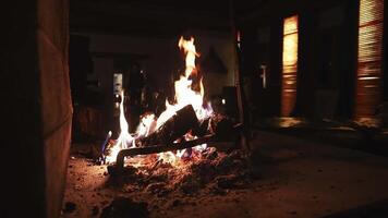 A serene indoor scene featuring a lit fireplace with dancing flames and glowing embers. Wooden blinds and furniture add to the tranquil ambiance. video