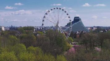 Riga Victory Park features a Ferris wheel in motion, cherry blossoms in full bloom, and the National Library of Latvia in the background. video