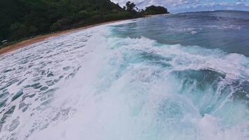 Aerial view of a tranquil Hawaiian beach with golden sand, lush vegetation, small houses, and steep forested hills in the background. video