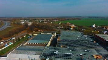Factory with solar panels on roof in the countryside. Flight along industrial plant with sunny batteries construction. Sustainable energy system. Aerial view. video