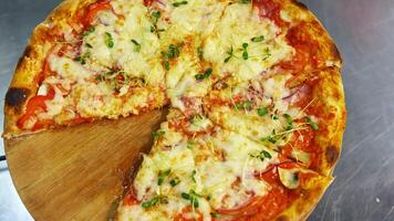 Tasty pizza in restaurant. Fresh round pizza with cheese and green sprouts on top rotating on a wooden board on a table. Ready pizza without one part portion. Close-up. video