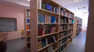Wooden bookcases in the library. Different books on bookshelves inside the light library room. Education and knowledge concept. video
