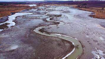seco lago. ecológico desastre dentro ambiente. global aquecimento. tortuoso rio em sujo fundo. movimento Câmera voltar. aéreo visualizar. video