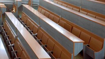 Modern desks in lecture hall. Rows of long wooden tables with vacant seats in the light auditorium at university. Classroom without students. video