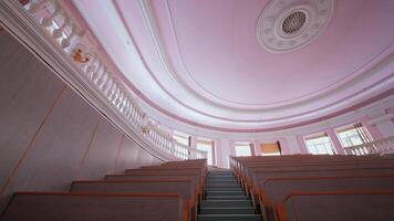 Empty auditorium at university. Large classroom with rows of wooden desks without students. Steps among tables in the large lecture hall. Pandemic. video