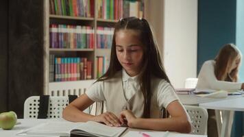 Caucasian teen girl calm little kid daughter studying at classroom concentrated pupil student read book search learn text in library young reader schoolgirl child reading textbook knowledge in school video