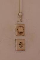 Old electrical switch and socket on wall showing signs of dirt and damage photo
