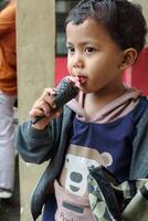 Kid enjoying strawberry ice cream cone with happy face in outdoor scene photo