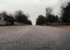 Road with a lot of trees and a red car parked on the side photo