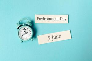 Clock and a piece of paper with the word Environment Day written on it photo