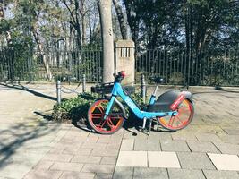 Cologne, Germany - March 19, 2022 - Blue bike with red wheels is parked in front of a fence photo