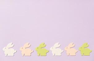 Row of rabbits in different colors are arranged on a purple background photo