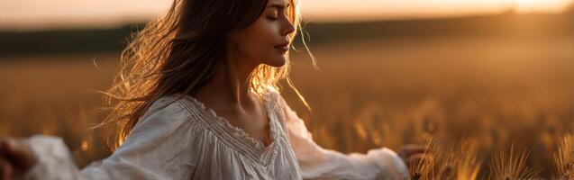 Woman enjoying sunset in golden field of grain photo