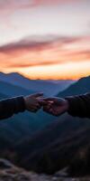 Hands connecting at sunset on a mountain peak photo