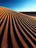 Shadows and patterns on a golden sand dune at sunset photo