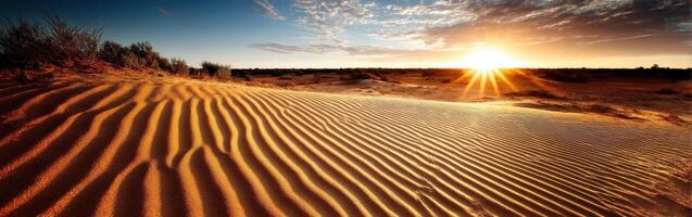 Desert sunrise illuminates rippled sand dunes and sky photo