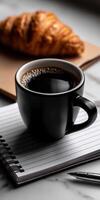 Coffee and croissant on notepad with pen on white background photo