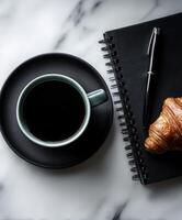 Morning coffee with croissant and notebook on marble photo