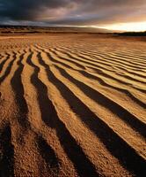 Sand dunes at sunset with clouds in the background photo