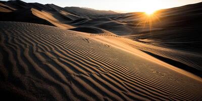 The sun is setting over a desert with sand dunes photo