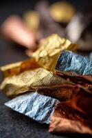 A pile of foil wrapped candies on a black surface photo