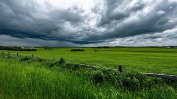 A field with green grass and a fence under a stormy sky photo
