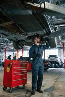 Fixing broken vehicle.,. Car repairman is in the garage with automobile photo