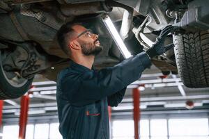Under, the,, vehicle, fixing. Car repairman is in the garage with automobile photo