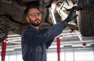 Under the vehicle, fixing.,, Car, repairman is in the garage with automobile photo