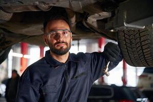 Fixing broken vehicle. ,Car repairman is in the garage with automobile photo
