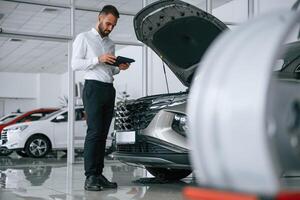 Worker ,in formal clothes is in the auto salon photo