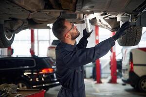 Under the,vehicle, fixing. Car repairman is in the garage with automobile photo