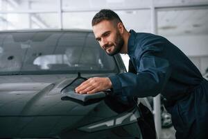 Process of polishing the surface with cloth. Car repairman is in the garage with automobile photo