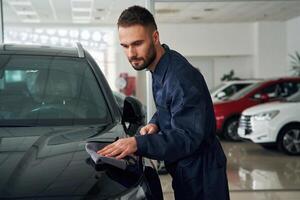 Polishing the vehicle. Car repairman, is, in the garage with automobile photo