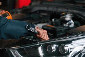 In blue colored ,uniform... Car repairman is in the garage with automobile photo