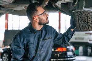 Under the vehicle, fixing,. Car repairman is in the garage with automobile photo