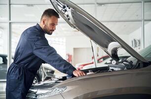 Hood, of vehicle is opened.., Car repairman is in the garage with automobile photo