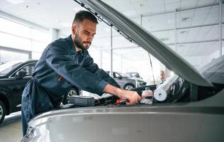 Focused ,on, fixing, the vehicle. Car repairman is in the garage with automobile photo