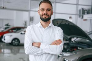 Portrait ,of beautiful man. Worker in formal clothes is in the auto salon photo