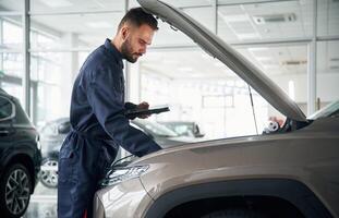 View ,from the ,side. Car repairman is in the garage with automobile photo